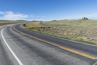 two lines on the road on a sunny day in wyoming, usa, with a black truck at left, and mountain scene behind