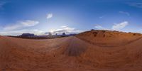 this 360 - cam shot shows a view of a desert with a rocky formation and a distant blue sky