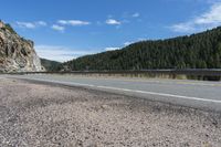 a view of the side of a road, from a vantage overlooking mountains and a valley