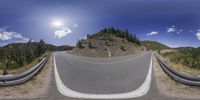 a 360 - turn photo of a bike rider on the road in the hills surrounding