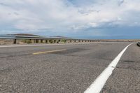 an empty street leading over a long, stretch of highway with mountains in the distance