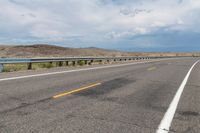 an empty street leading over a long, stretch of highway with mountains in the distance