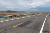 an empty street leading over a long, stretch of highway with mountains in the distance