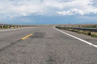 an empty street leading over a long, stretch of highway with mountains in the distance