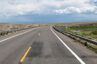 an empty street leading over a long, stretch of highway with mountains in the distance