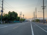 an empty street in front of a large red brick building on the other side of the road is a street light that has a line for motorists