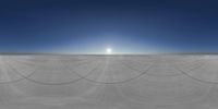 a view of a white concrete skate ramp under blue skies with the sun reflecting over it