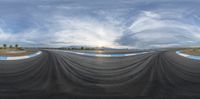 a big cloud hangs over an empty highway as a man rides on the bike down a curve