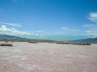 a vast desert with large rocks all around it's surface and mountains in the background