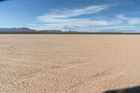 an arid area with dry grass and dirt roads and mountains in the distance with blue skies