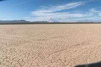 an arid area with dry grass and dirt roads and mountains in the distance with blue skies