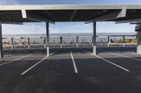 an empty parking lot with a parking structure that holds multiple poles and a walkway at each corner