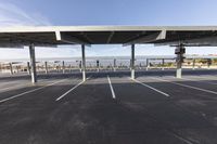 an empty parking lot with a parking structure that holds multiple poles and a walkway at each corner