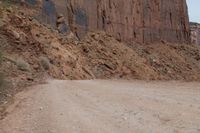 a truck parked on the side of a dirt road in a canyon surrounded by high cliffs