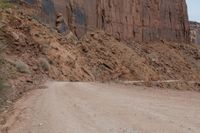 a truck parked on the side of a dirt road in a canyon surrounded by high cliffs