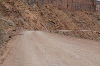 a truck parked on the side of a dirt road in a canyon surrounded by high cliffs