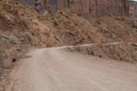 a truck parked on the side of a dirt road in a canyon surrounded by high cliffs