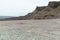 a dirt road leading to a valley of hills and barren ground with a truck driving through it