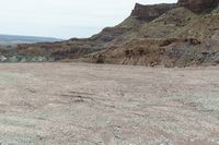 a dirt road leading to a valley of hills and barren ground with a truck driving through it