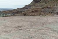 a dirt road leading to a valley of hills and barren ground with a truck driving through it