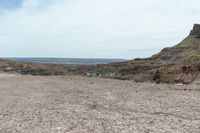 a dirt road leading to a valley of hills and barren ground with a truck driving through it