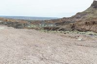 a dirt road leading to a valley of hills and barren ground with a truck driving through it