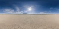 a wide shot of the sun shining over a vast desert landscape with a mountain backdrop