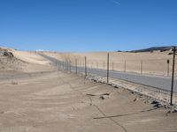 a paved beach with a fence in front of it and the ocean in the distance