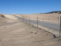 a paved beach with a fence in front of it and the ocean in the distance