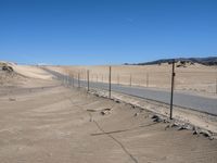 a paved beach with a fence in front of it and the ocean in the distance