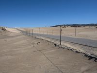 a paved beach with a fence in front of it and the ocean in the distance