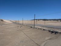 a paved beach with a fence in front of it and the ocean in the distance