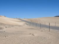 a paved beach with a fence in front of it and the ocean in the distance