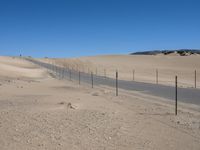 a paved beach with a fence in front of it and the ocean in the distance