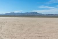 a large sand field with no people in it, and mountain range in the background