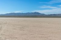 a large sand field with no people in it, and mountain range in the background