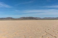 the desert is dry and barren with sparse clouds in the sky and a few mountains in the background