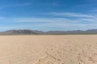 the desert is dry and barren with sparse clouds in the sky and a few mountains in the background