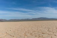 the desert is dry and barren with sparse clouds in the sky and a few mountains in the background