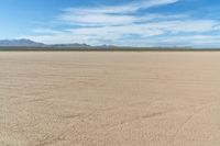 a motorcycle in the middle of an empty plain plain with lots of dirt and mountains