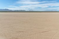 a motorcycle in the middle of an empty plain plain with lots of dirt and mountains