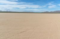 a motorcycle in the middle of an empty plain plain with lots of dirt and mountains