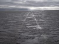 a wide paved desert road going through the middle of nowhere under a cloudy sky,