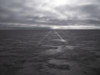 a wide paved desert road going through the middle of nowhere under a cloudy sky,