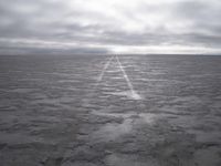 a wide paved desert road going through the middle of nowhere under a cloudy sky,