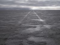a wide paved desert road going through the middle of nowhere under a cloudy sky,