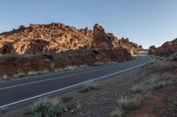 a long road winds its way through some red desert mountains in the usa for a hike