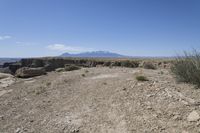 a view over a vast and barren landscape with rock formations in the distance and a small rock arch