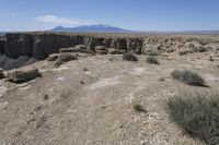 a view over a vast and barren landscape with rock formations in the distance and a small rock arch