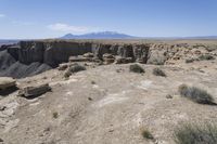 a view over a vast and barren landscape with rock formations in the distance and a small rock arch